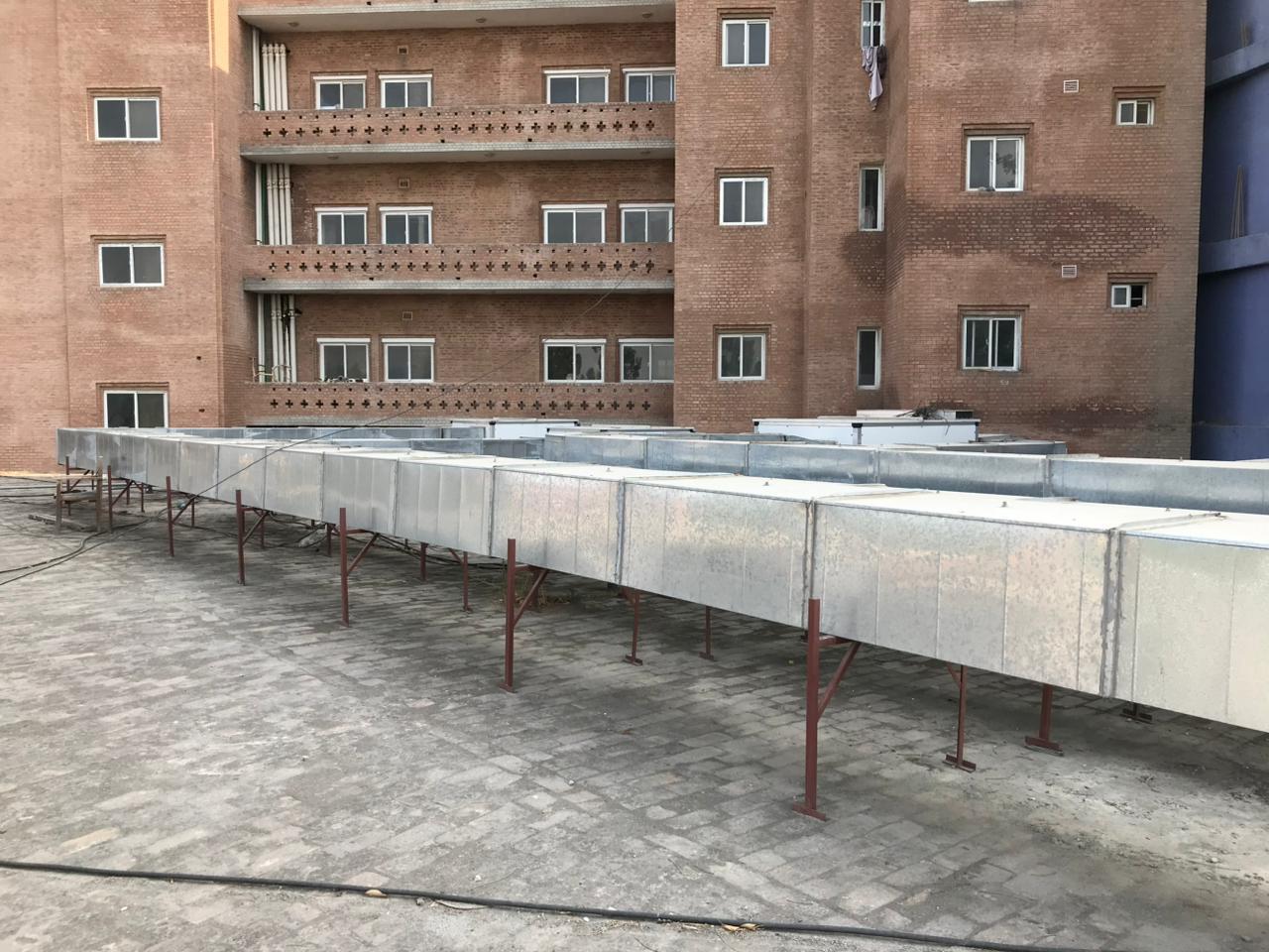 Workers installing ducts on scaffolding at hospital